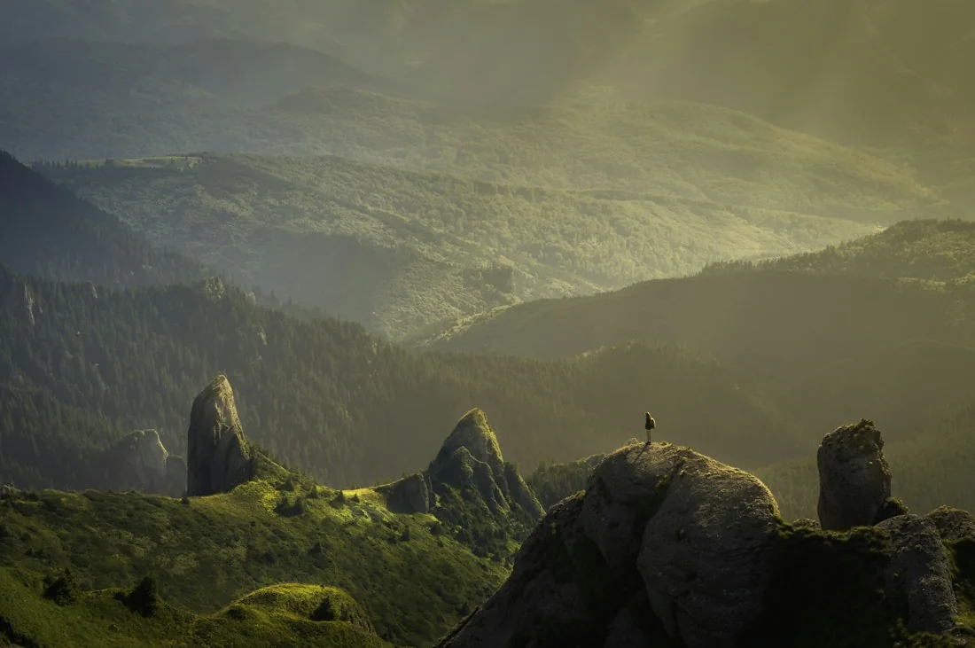 Layers of forest and mountain ridges opening onto a sunlit horizon.